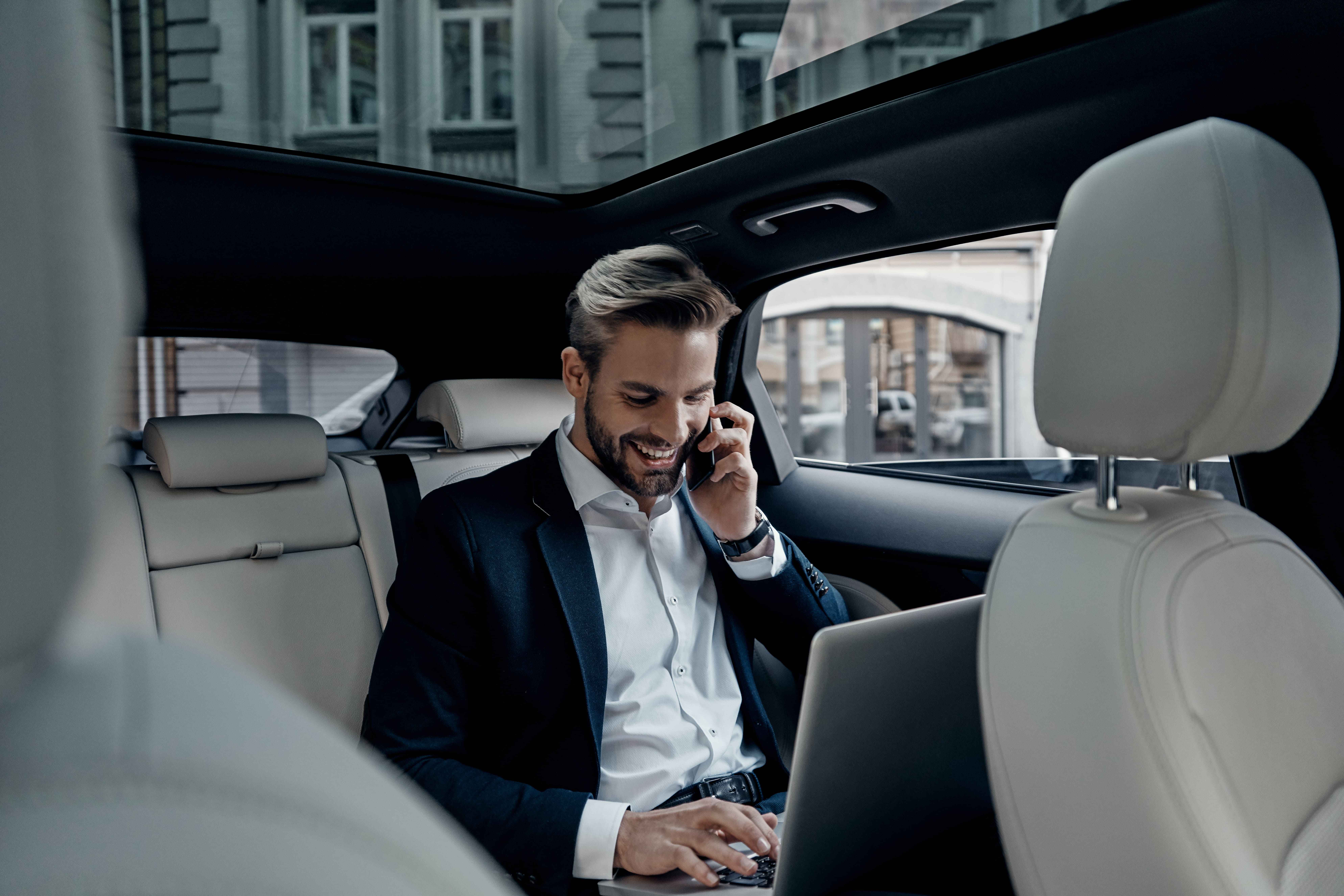 discussing-business-details-handsome-young-man-full-suit-talking-smart-phone-smiling-while-sitting-car
