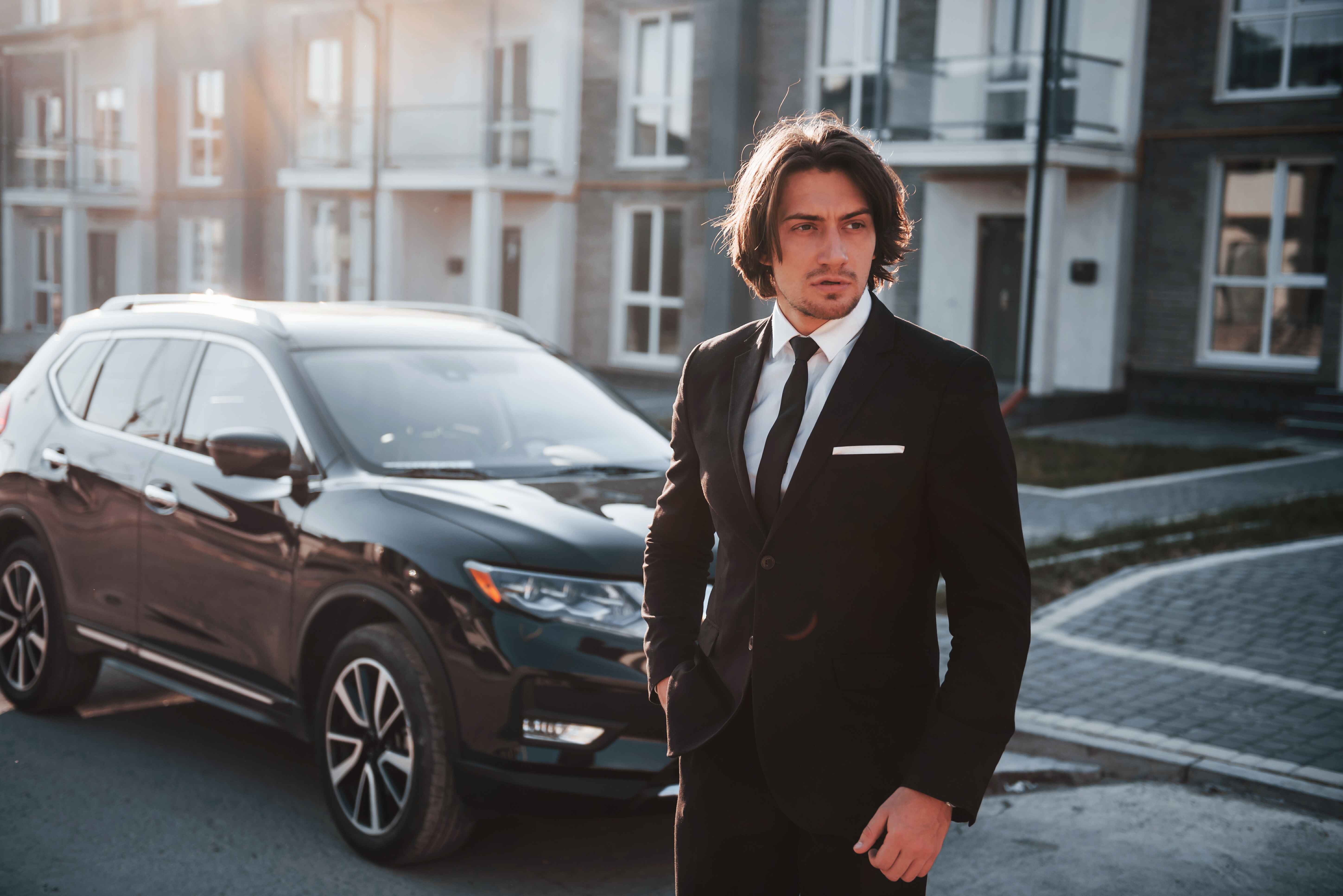 portrait-handsome-young-businessman-black-suit-tie-outdoors-near-modern-car-city_1